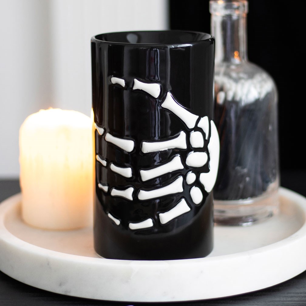 black oil burner featuring a skeletal hand wrapped around the base