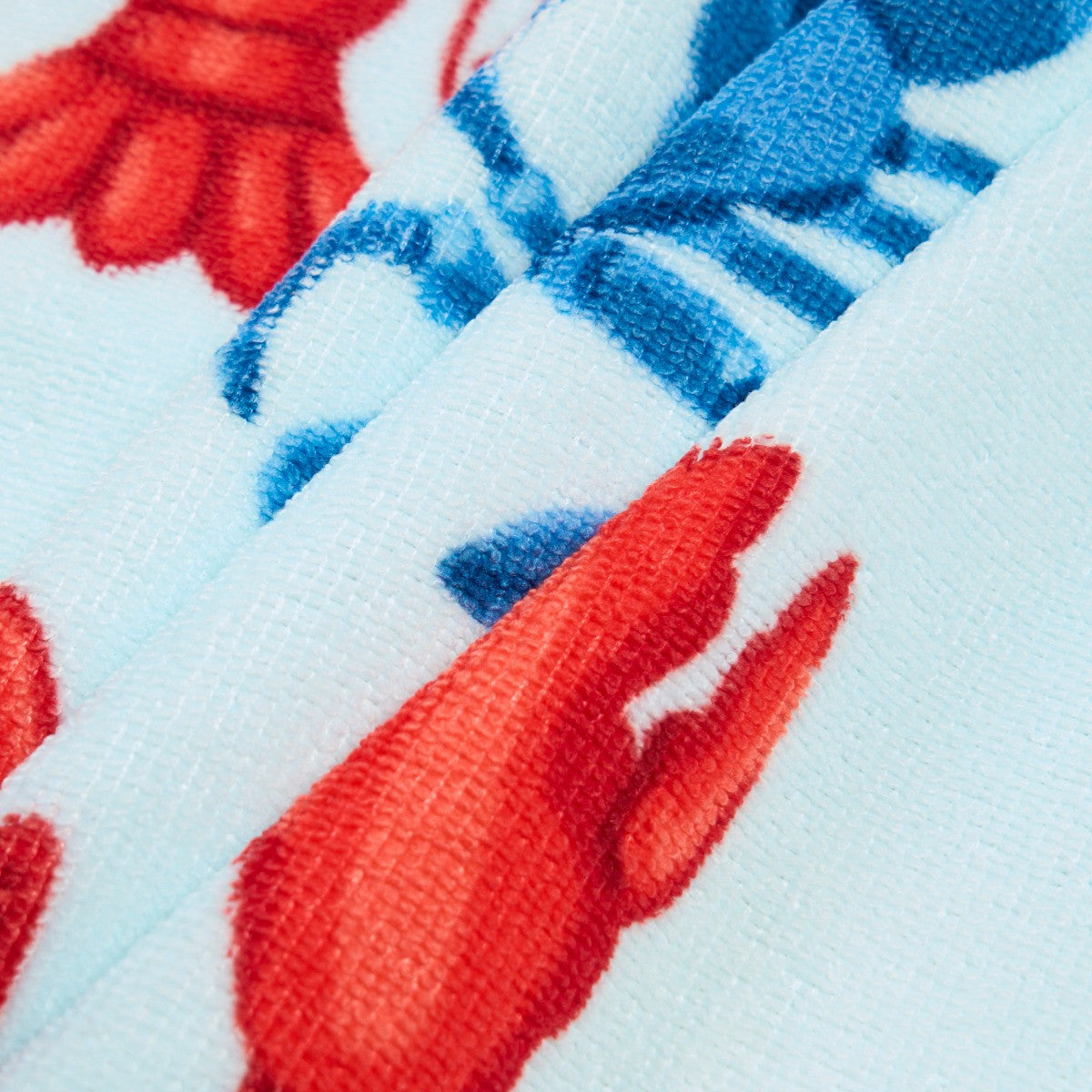 Detailed close-up of lobster print texture on blue beach towel