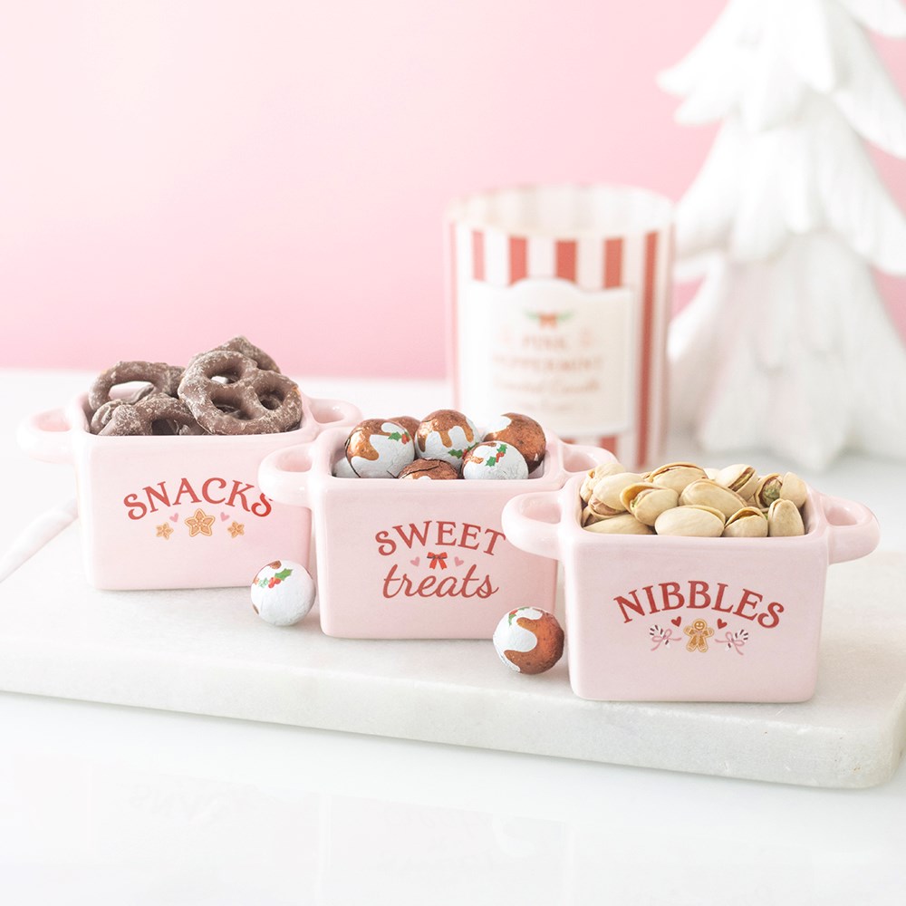 three sugarplum bakery christmas snack bowls filled with festive treats at a party