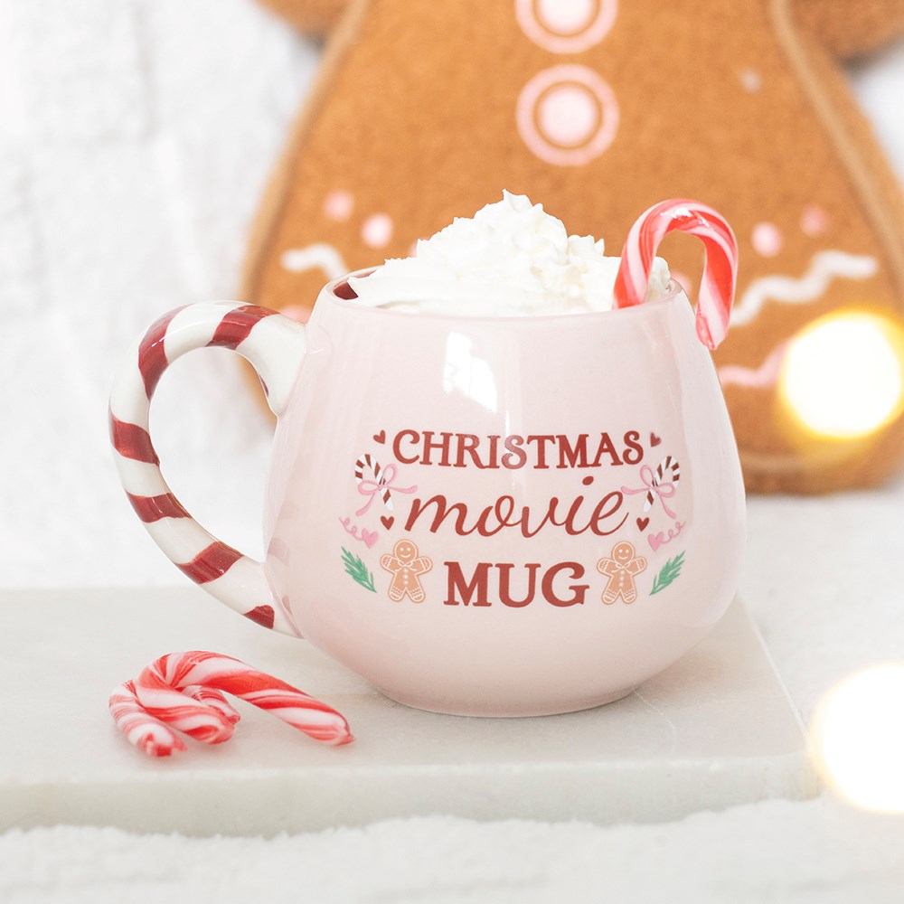 pink christmas movie mug with candy cane style handle in a cosy home setting