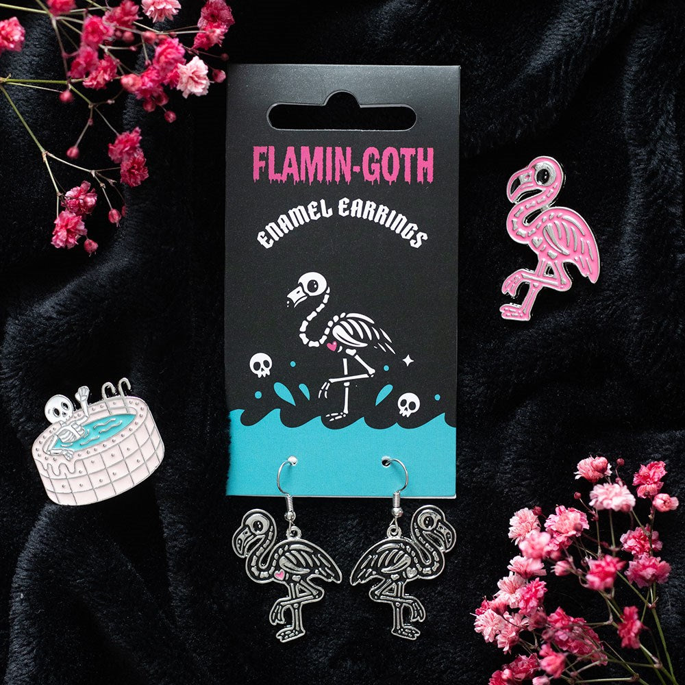 flamin-goth skeletal flamingo dangle earrings displayed on a card in a gothic setting
