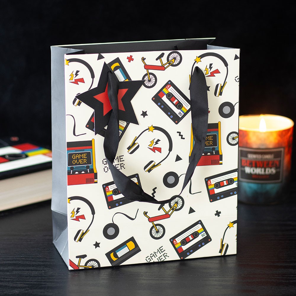 retro 80s print gift bag displayed in a home setting with cassette tapes and arcade inspired designs