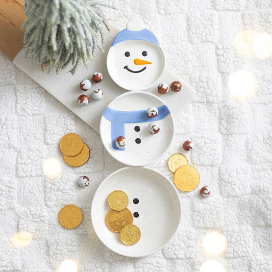 three christmas snowman stacking bowls filled with chocolate coins and sweets in a home setting
