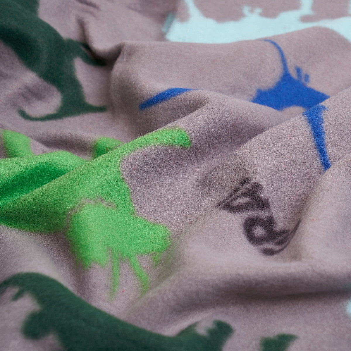close up detail of soft polar fleece dinosaur blanket texture and print