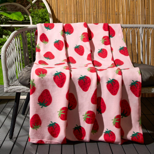 strawberry fleece throw draped over garden bench showing playful strawberry pattern design