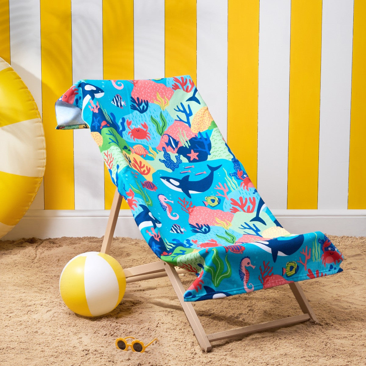 beach towel with ocean-themed sea life illustration draped over deck chair