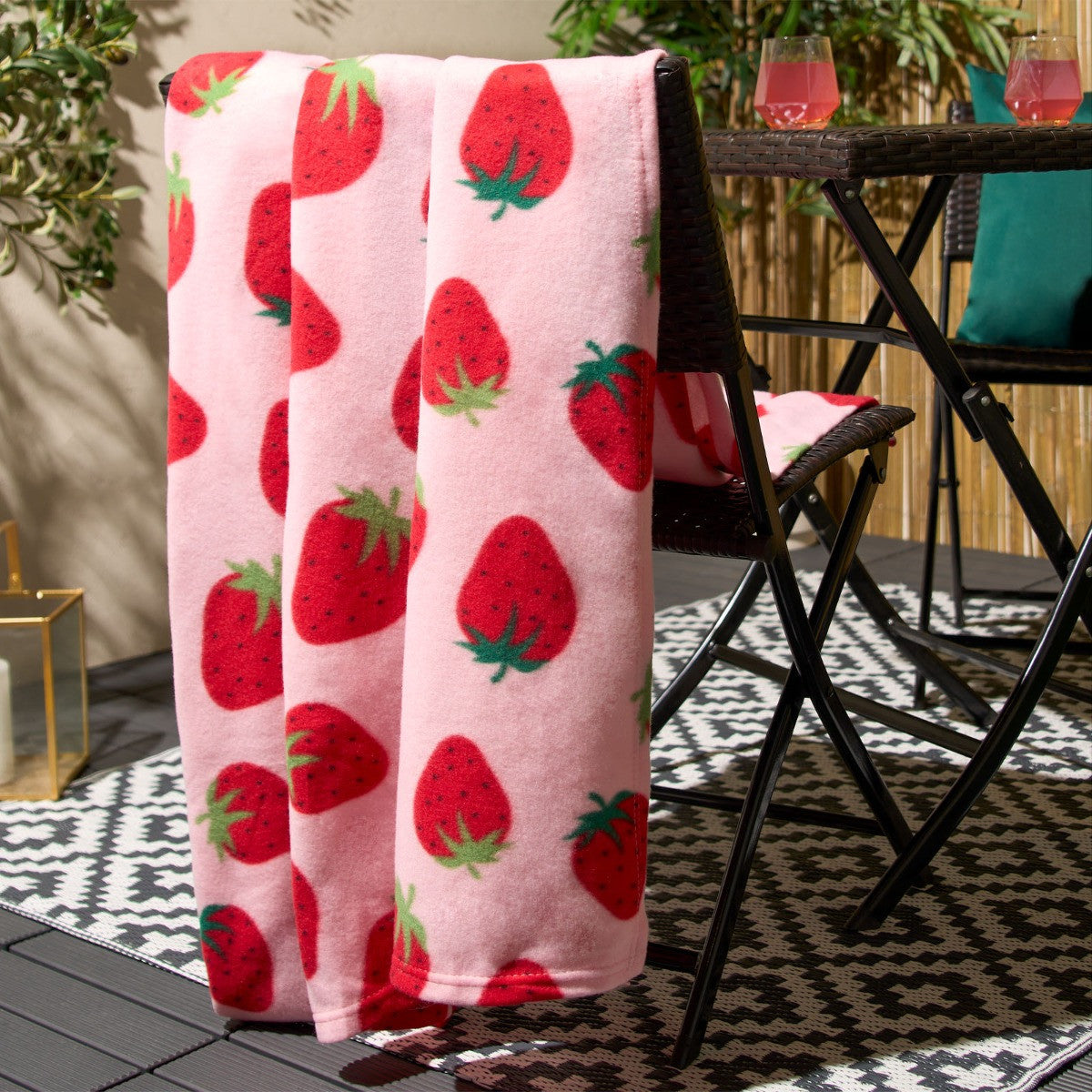 strawberry fleece throw draped over chair back displaying full surface pattern