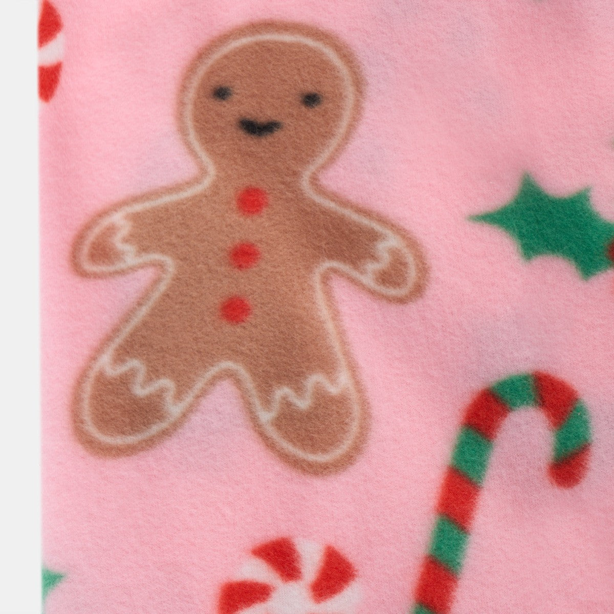 close-up of pink gingerbread fleece throw, focusing on the gingerbread man pattern and vibrant colours