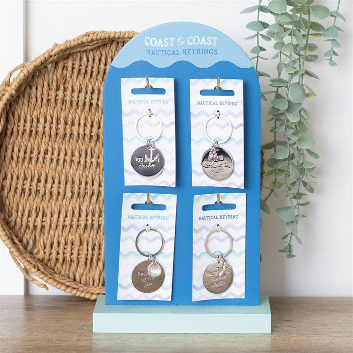 four nautical keyring designs displayed vertically on a stand in a seaside themed setting