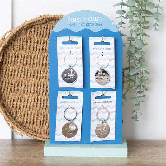 four nautical keyring designs displayed vertically on a stand in a seaside themed setting
